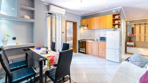 Un espace de vie compact comprenant un coin repas, une kitchenette et un lit.