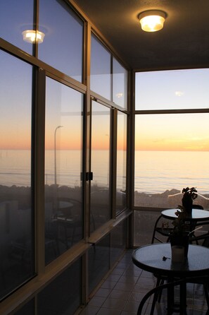 Enjoy ocean views from the large windows in this serene room, featuring a small table and chair.