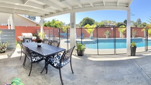 A covered patio area with a pool, outdoor furniture, and potted plants. - Kids Love Us! Legoland Home with A Pool (Oceanside)