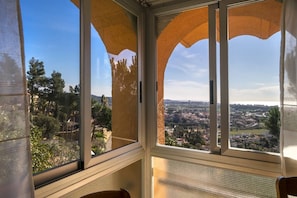 A room with large windows offering a view of a cityscape and greenery.