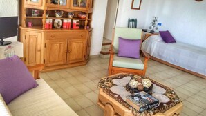 Uma sala de estar acolhedora com um armário de madeira, um sofá, uma poltrona e uma mesa de centro.