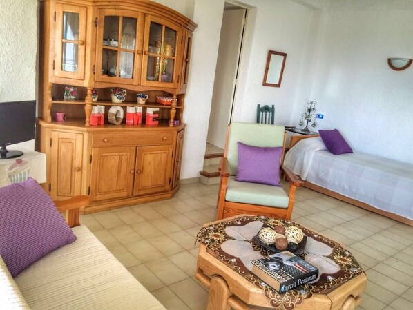 A living room with a wooden cabinet, a sofa, a chair, and a coffee table. - Ca la Mireia - The tranquility of the mountain near the sea with Wifi and AACC (Calonge)