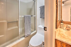 Ein Badezimmer mit einer Duschkabine, einer Toilette und einem Waschtisch mit Spiegel und Seifenspender.
