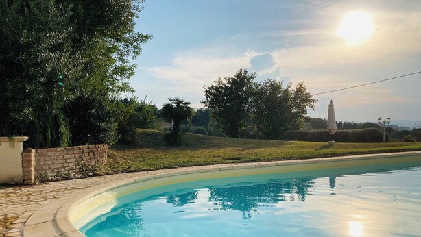 A swimming pool with a stone border, surrounded by greenery and a brick wall. - Great villa with pool, free wifi, beach, sea, last minute, Italy (Montelabbate)