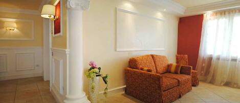 A living room with a sofa, a vase with flowers, and a painting on the wall.