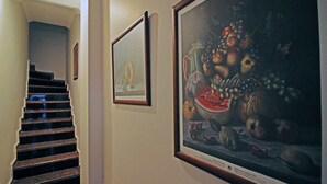 A staircase leading to a landing with framed artwork on the wall. - Bozcaada Balci Hotel (Bozcaada)