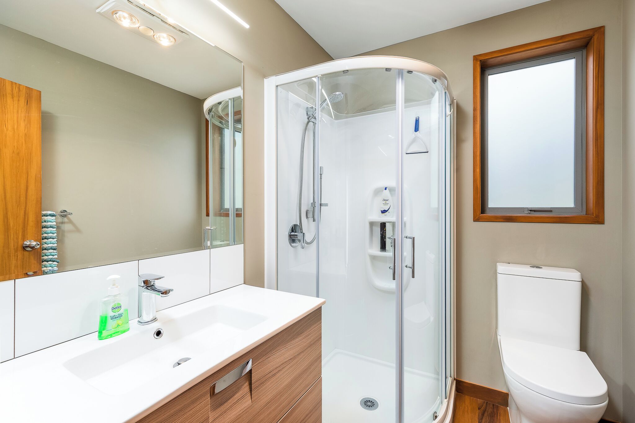 A modern bathroom with a glass-enclosed shower, a white sink, and a toilet.