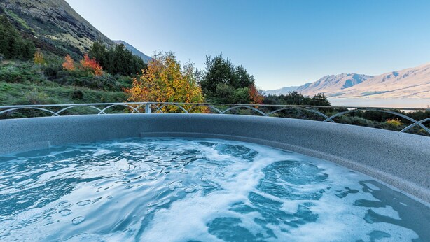 Un jacuzzi con vistas despejadas a un paisaje montañoso y follaje otoñal.