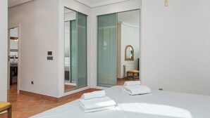 Un dormitorio moderno con una cama grande, un baño con ducha de vidrio y vista al área de estar.