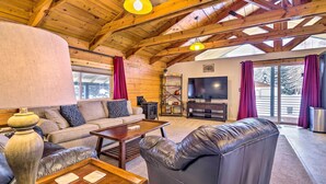 A cozy living room with a wooden ceiling, leather sofa, and a flat-screen TV. - McCall Retreat w/ Hot Tub - 1/2 Mi to Downtown! (McCall)