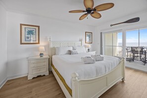 Ein Schlafzimmer mit einem Bett, Nachttischen, einem Deckenventilator und Blick ins Freie.