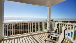 Un balcon fermé offrant une vue sur la plage et l’océan.