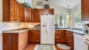 Una cocina con armarios de madera, un refrigerador blanco y una encimera de granito.