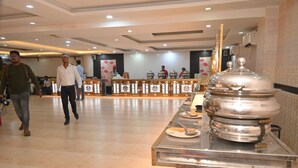 A hotel lobby with a buffet area, a reception desk, and a large decorative urn.