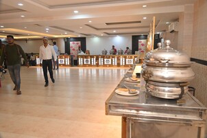 A hotel lobby with a buffet area, a reception desk, and a large decorative urn.