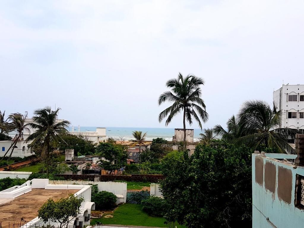 Zona residencial com vista para o mar, palmeiras e edifícios brancos.