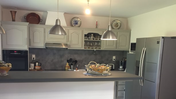 Una cocina moderna con gabinetes blancos, un refrigerador de acero inoxidable y dos taburetes de bar.