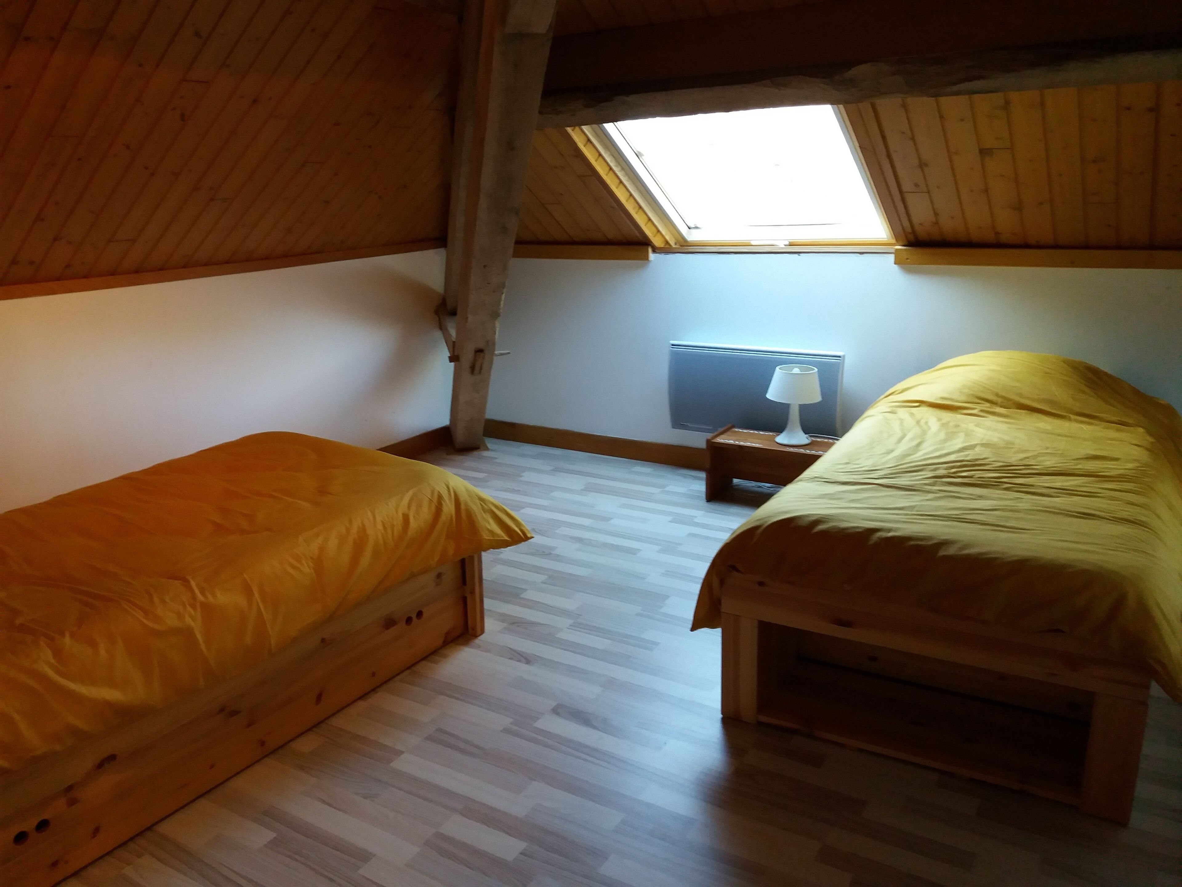 A small, cozy room with two wooden beds, a small table, and a radiator.
