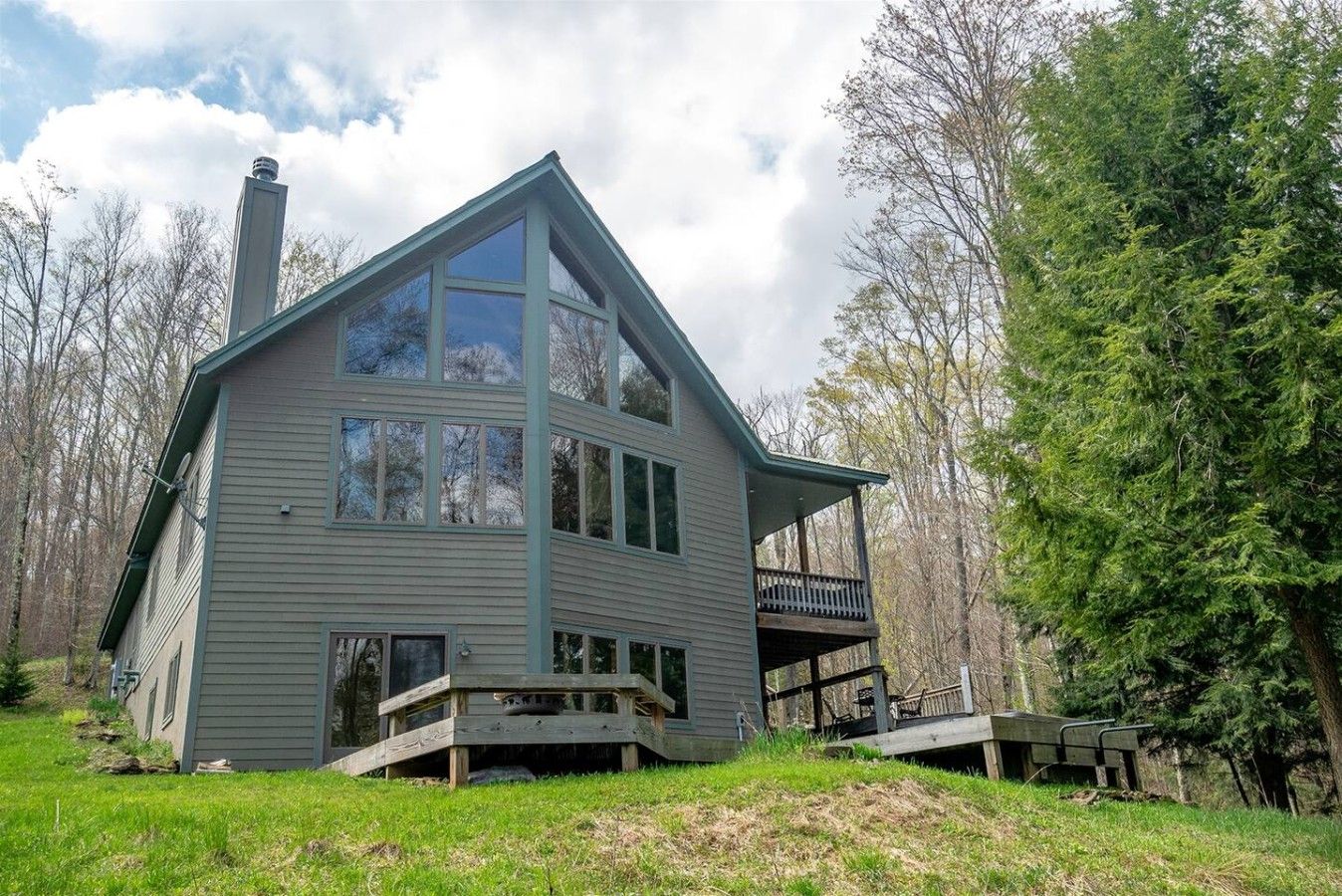 A two-story house with a balcony, surrounded by trees.