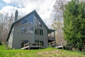 A two-story house with a balcony, surrounded by trees.