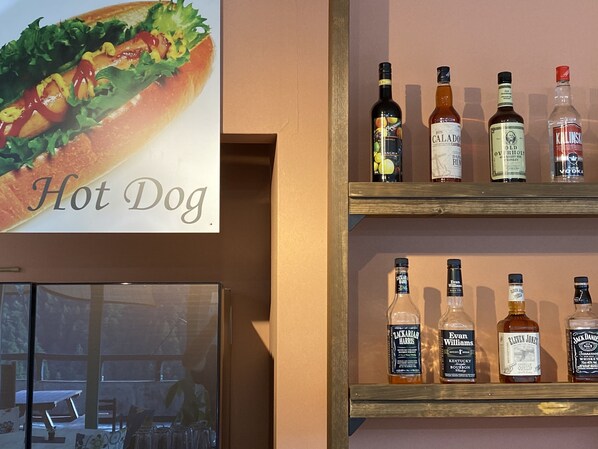 A restaurant interior with a menu board displaying a hot dog and a selection of whiskey bottles on shelves.