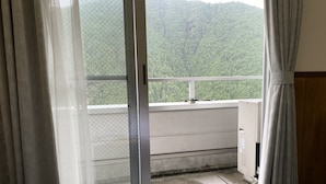 Une chambre d’hôtel avec un lit, une fenêtre avec des rideaux et une vue sur une zone boisée.