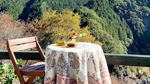 Une table recouverte d’une nappe à motifs et un banc, d’où l’on peut admirer un paysage montagneux.