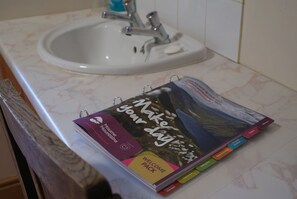 Ein Badezimmer mit einem Waschbecken und einem Buch mit dem Titel 'Make your day' auf der Ablagefläche.