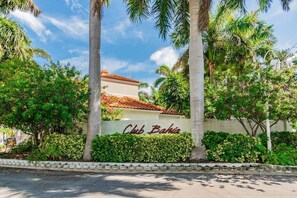 Un edificio con un cartello che riporta 'Club Bahia', circondato da vegetazione lussureggiante e palme.