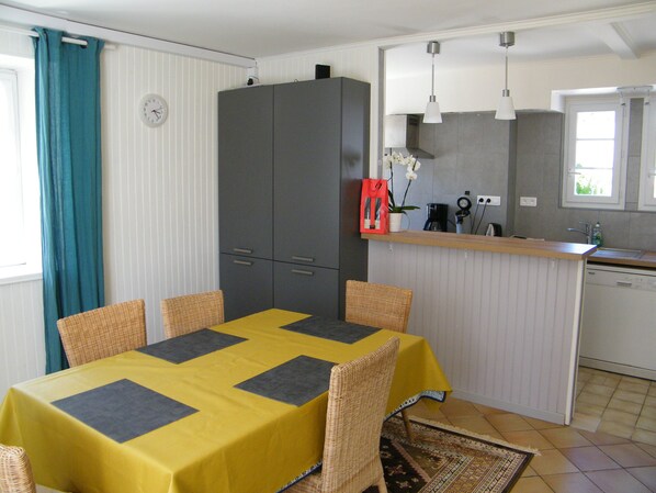 A compact kitchen with a dining area. It includes a table with chairs, a cabinet, a sink, and a window.