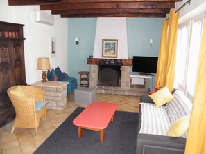 A cozy living room with a stone fireplace, a television, and comfortable seating.