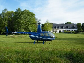 A blue helicopter with registration F-GZEB parked on a grassy field.