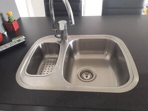 A stainless steel kitchen sink with a double basin and a single drain.