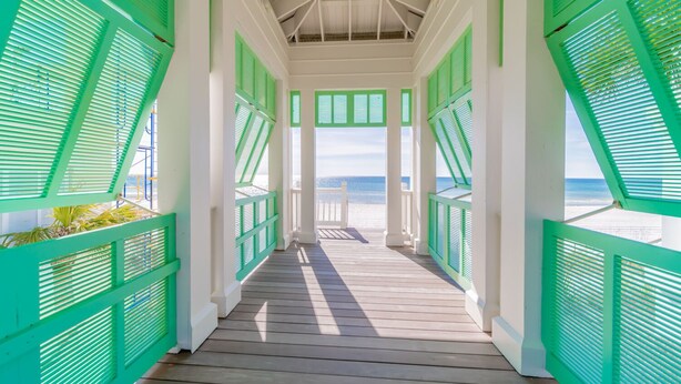 A wooden deck with green shutters leading to a beach view. - "Sea La Vie" | Gulf & Lakefront Views | Community Heated Pool | Tennis, Pickleball, Basketball (Panama City Beach)