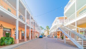 A street with multi-story buildings, a paved road, and string lights. - "Sea La Vie" | Gulf & Lakefront Views | Community Heated Pool | Tennis, Pickleball, Basketball (Panama City Beach)