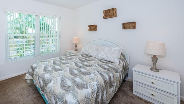 A bedroom with a bed, two bedside tables, a window with blinds, and three wall-mounted baskets. - Waterfront 2BR condo in St. Petersburg with balcony, pool, and water views. (St Petersburg)
