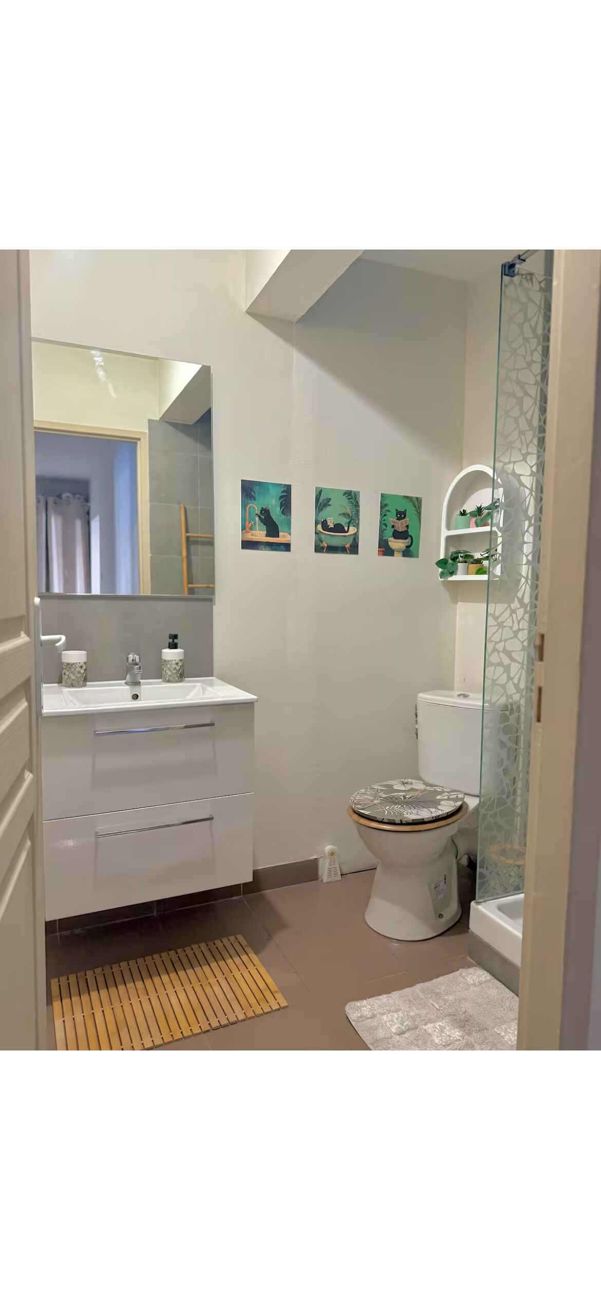 A bathroom with a white vanity, a toilet, and a shower area.