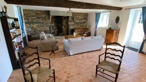 A spacious living room with a stone fireplace, a white sofa, and two wooden chairs. - House 200 m2 for 11 people with heated swimming pool. (STE ANNE SUR VILAINE)