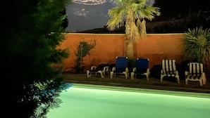 Un espace piscine avec des chaises longues et un palmier.