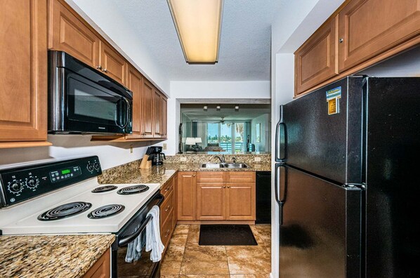 A kitchen with wooden cabinets, a stainless steel refrigerator, a microwave, and a stove.