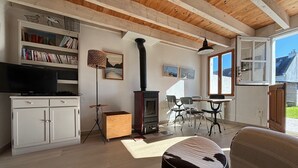Ein geräumiges Wohnzimmer mit Kamin, Fernseher und Essbereich mit Stühlen.