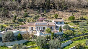 Una casa a due piani con piscina, immersa nel verde e circondata da colline.