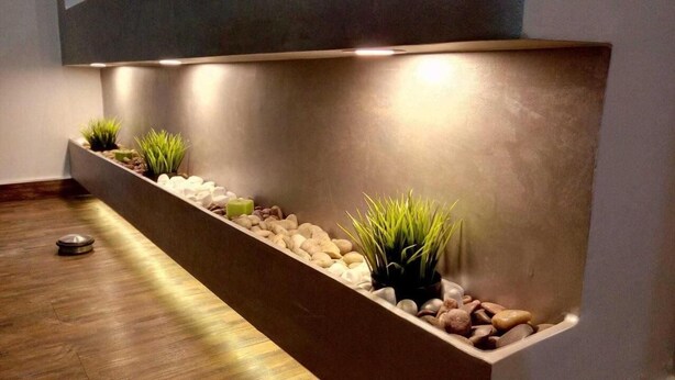 A modern reception area with a long, narrow planter filled with rocks and small plants, illuminated by overhead lighting. - Elite Residency (Amman)