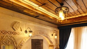 A cozy bedroom with a wooden ceiling, a large bed with dark bedding, a wooden nightstand, and a patterned rug. - Wonder of Cappadocia (Nevsehir)