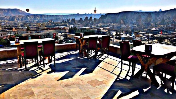 An outdoor seating area with tables and chairs, overlooking a cityscape with mountains in the background. - Wonder of Cappadocia (Nevsehir)