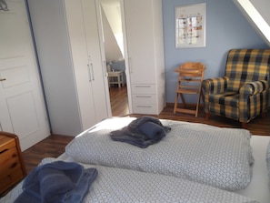 A bedroom with a bed, a chair, a wardrobe, and a desk.