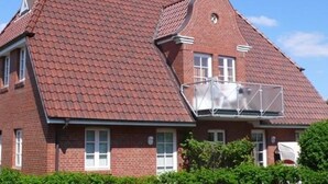 A two-story brick house with a red-tiled roof and a balcony with a metal railing. - Rungholtstr. 3 a, apt. jetsam (Wyk auf Föhr)