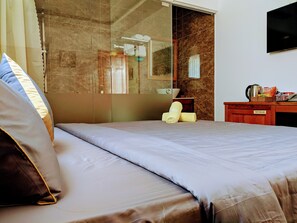 A hotel room with a bed, a bathroom with a glass shower enclosure, and a minibar. - Kim Ngan Hotel (Ho Chi Minh City)