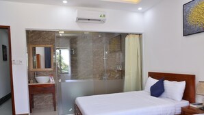 Una habitación de hotel con cama, mesita de noche y baño completo con ducha e inodoro.