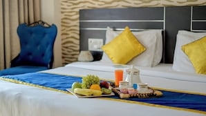 A hotel room with a neatly made bed, a tray of fruits and juice, and a breakfast setup. - BlueNeck Sec 40 Unitech Cyber Park Gurugram (Gurugram)